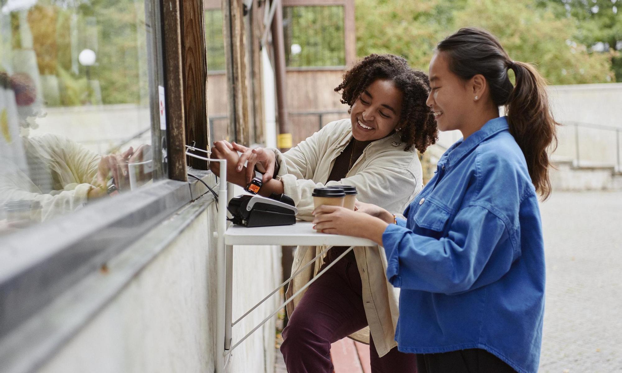 Two young adults pays with smart watch