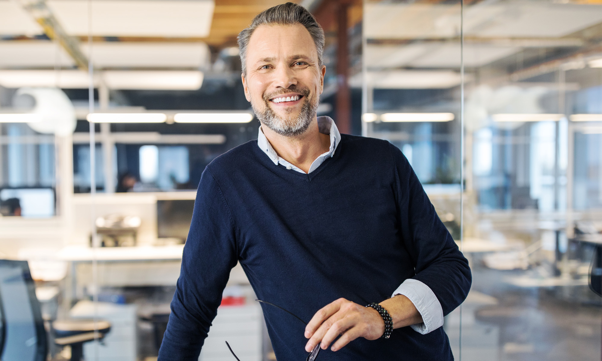 Man in office holding glasses