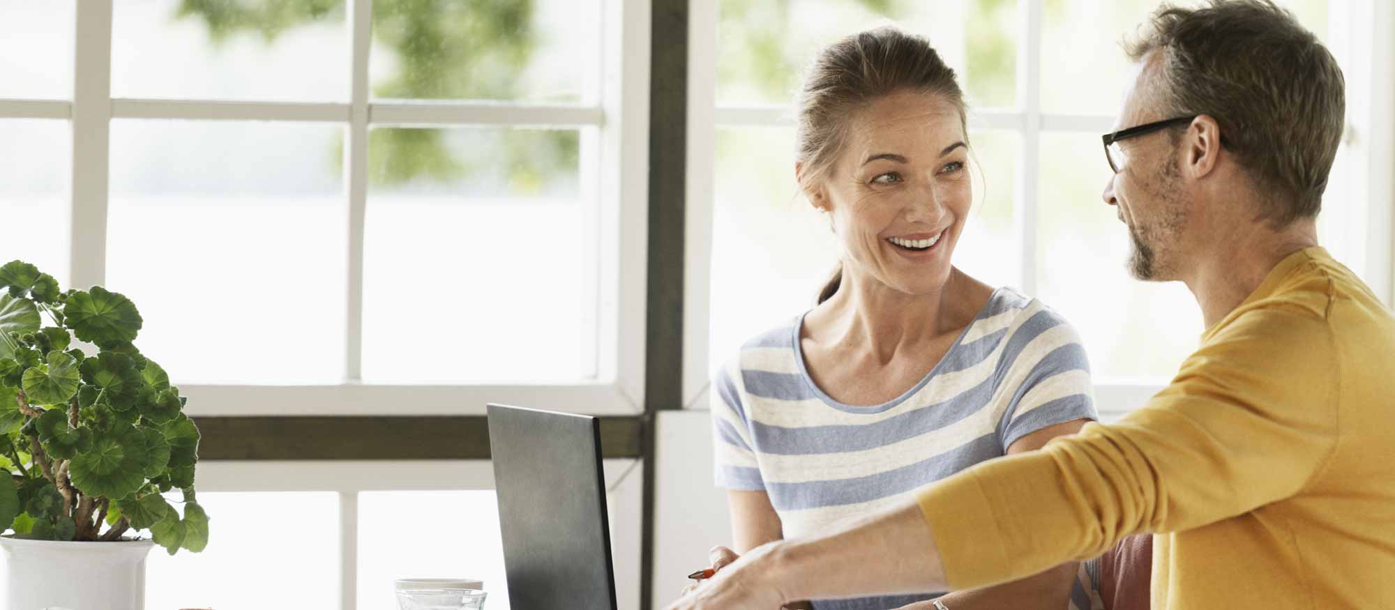 Par sitter vid en dator hemma på glasverandan